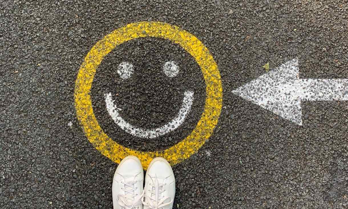 A smiley face painted on road with feet
