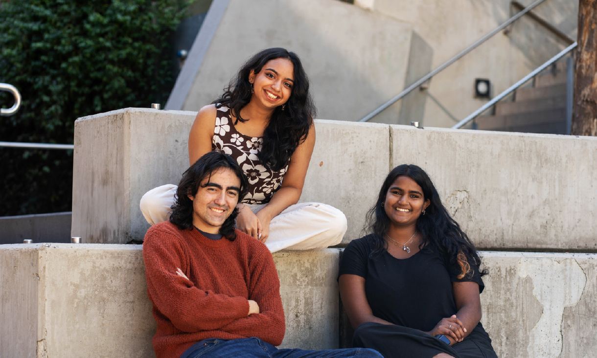 Three students sitting on concrete steps
